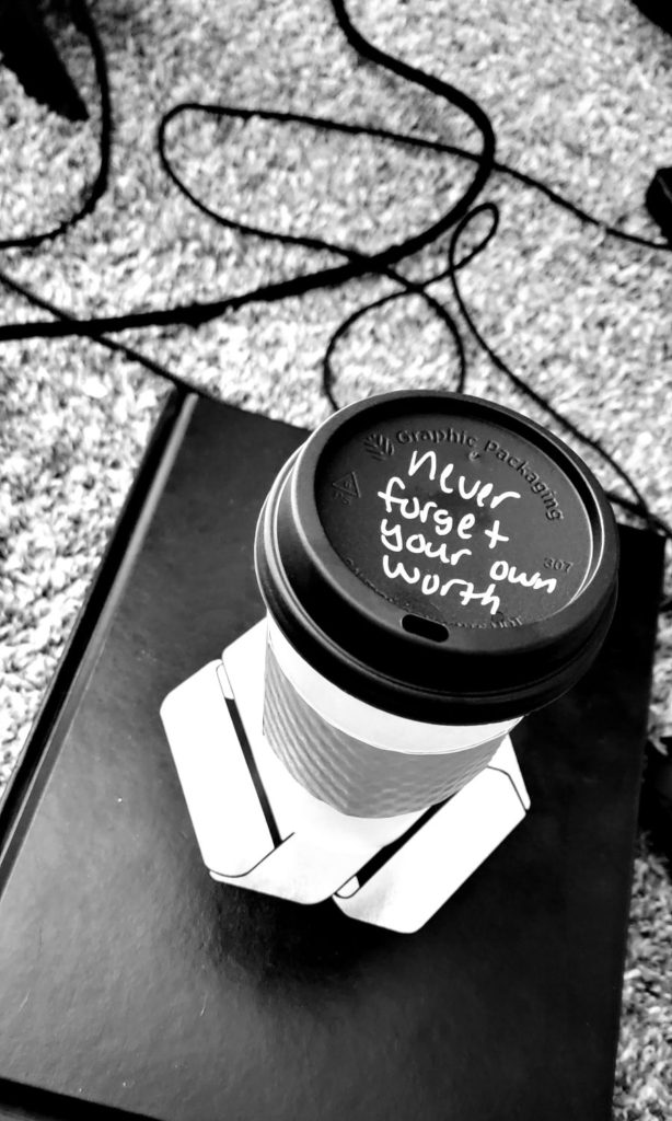 bl;ack and white image of a coffee cup sitting on top of a book